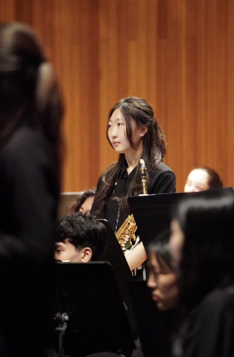 Senior Maria Park rises confidently after completing her saxophone solo. Years of dedication resonate through the applause that follows her powerful performance. 